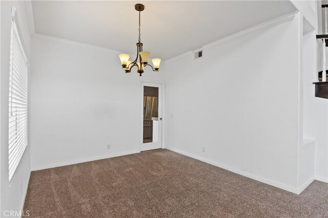 spare room featuring a chandelier, visible vents, carpet flooring, and ornamental molding