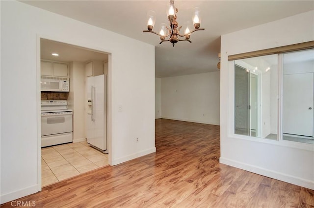 8566 Van Ness Ct Unit 21D, Huntington Beach, CA 92646 - kitchen with white appliances, a chandelier, light wood-style floors, and baseboards