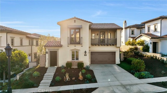 mediterranean / spanish-style house featuring a balcony, stucco siding, concrete driveway, an attached garage, and a tile roof