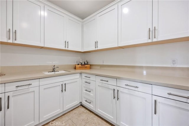 kitchen featuring a sink, light countertops, light tile patterned floors, and white cabinetry