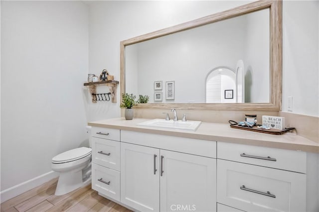 bathroom with toilet, baseboards, wood finished floors, and vanity