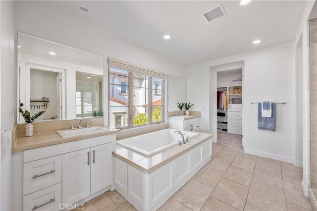 bathroom with a walk in closet, vanity, recessed lighting, visible vents, and a garden tub