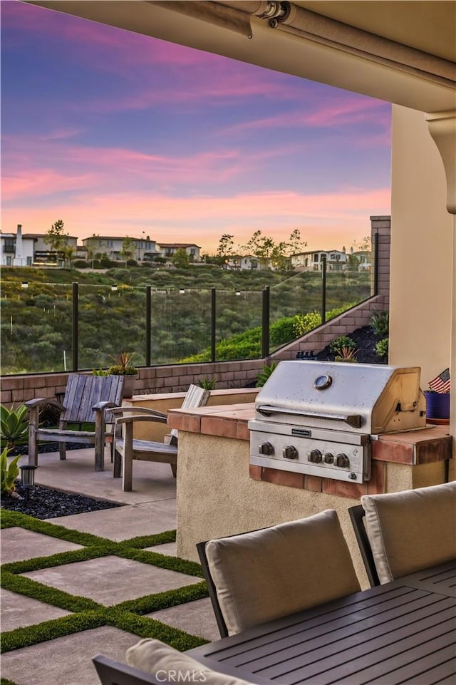 patio terrace at dusk with fence, grilling area, and area for grilling