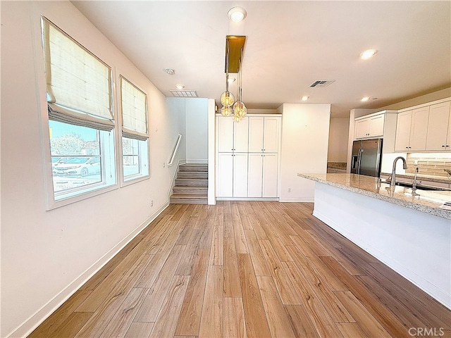 27078 Painted Sky Way, Valencia, CA 91381 - kitchen with refrigerator with ice dispenser, light wood-style floors, white cabinets, light stone countertops, and pendant lighting