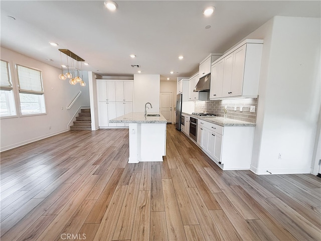 27078 Painted Sky Way, Valencia, CA 91381 - kitchen with stainless steel appliances, extractor fan, light wood-type flooring, decorative backsplash, and white cabinets