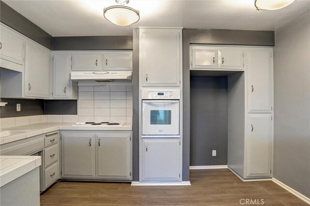 4343 Finley Ave Unit 35, Los Angeles, CA 90027 - kitchen with white appliances, under cabinet range hood, wood finished floors, tile counters, and backsplash