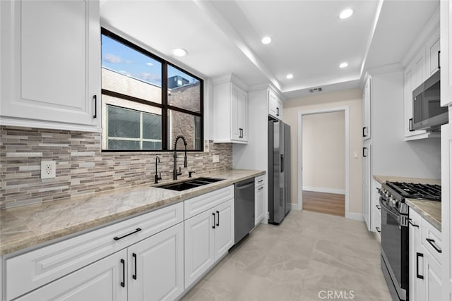 kitchen with white cabinetry, decorative backsplash, a sink, appliances with stainless steel finishes, and recessed lighting