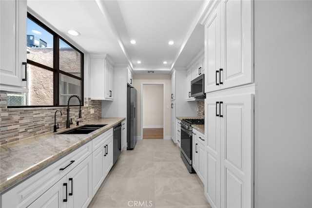 kitchen featuring a sink, white cabinets, appliances with stainless steel finishes, and tasteful backsplash