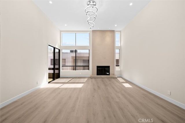 unfurnished living room with a glass covered fireplace, wood finished floors, recessed lighting, and baseboards