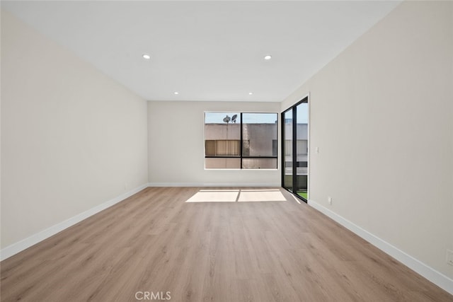 empty room with recessed lighting, light wood-style flooring, and baseboards
