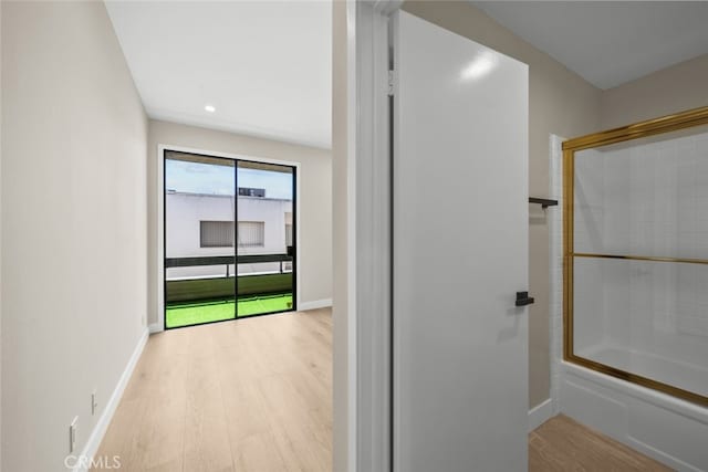 interior space featuring wood finished floors, recessed lighting, shower / bath combination with glass door, and baseboards