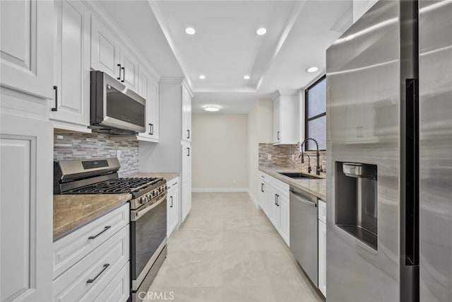 kitchen with recessed lighting, light stone countertops, a sink, decorative backsplash, and appliances with stainless steel finishes