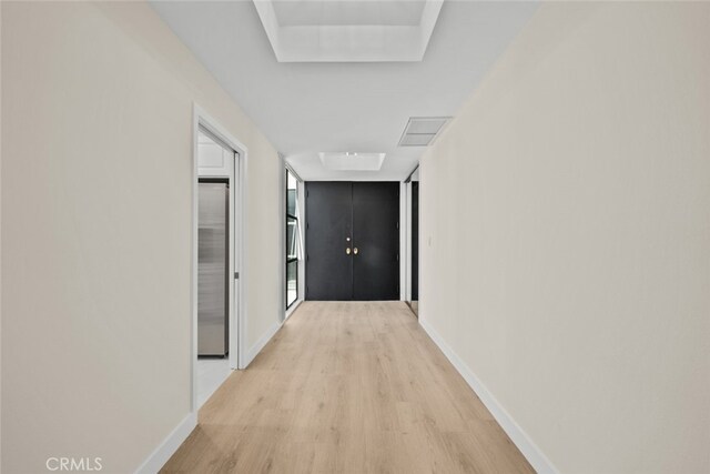 hallway with baseboards, light wood-type flooring, and visible vents
