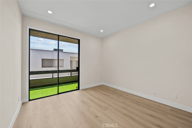 empty room featuring baseboards, light wood-type flooring, and recessed lighting
