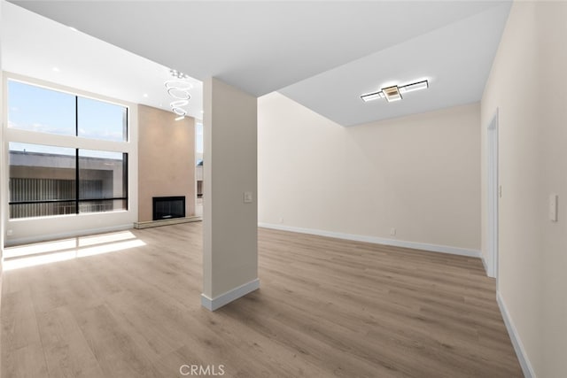 interior space with wood finished floors, a fireplace with raised hearth, and baseboards