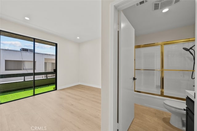 bathroom with wood finished floors, visible vents, toilet, and shower / bath combination with glass door