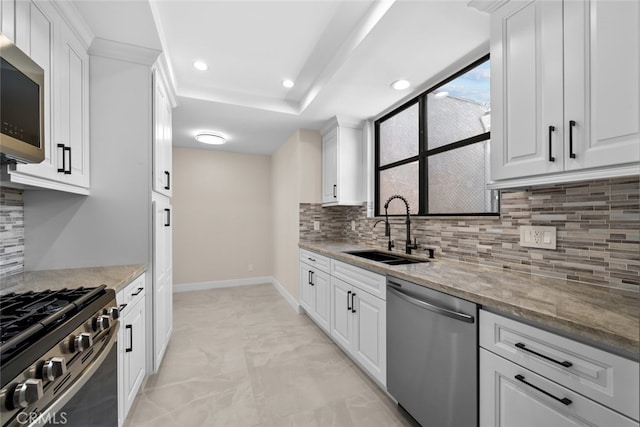 kitchen featuring white cabinetry, a sink, stainless steel appliances, light stone countertops, and recessed lighting