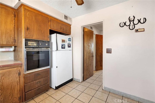 kitchen with brown cabinets, oven, ceiling fan, visible vents, and freestanding refrigerator