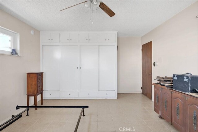 interior space featuring ceiling fan, a textured ceiling, and light tile patterned floors