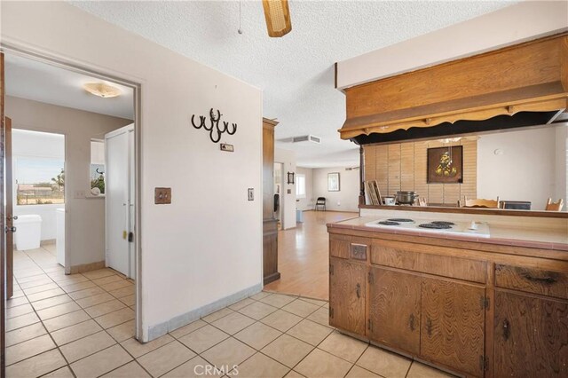 kitchen with a ceiling fan, a wealth of natural light, white electric cooktop, and light tile patterned floors