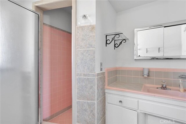 full bathroom with tile walls, vanity, and a tile shower