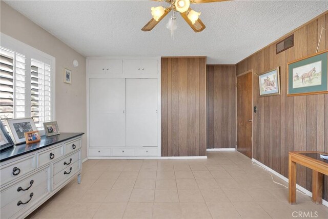 interior space with baseboards, visible vents, a textured ceiling, and wooden walls