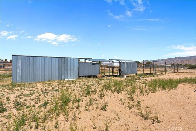 view of yard with fence, an outbuilding, a rural view, and a mountain view