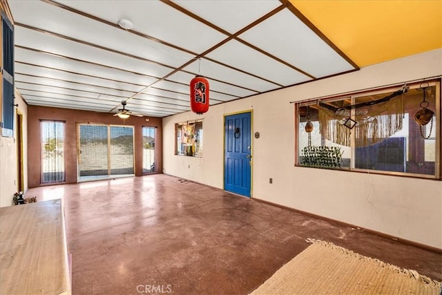 unfurnished room featuring baseboards, a ceiling fan, and finished concrete floors
