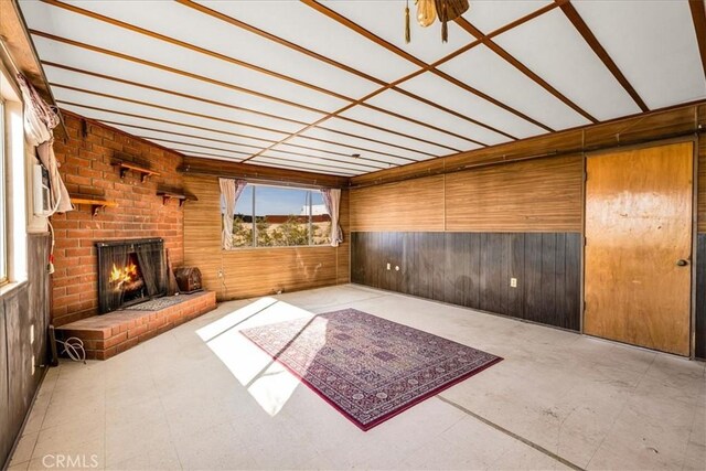 unfurnished living room with wooden walls and a fireplace