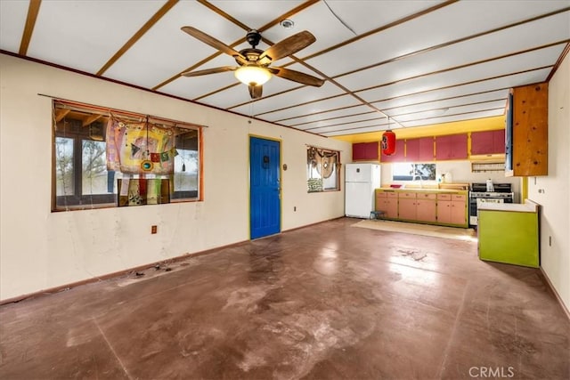 unfurnished living room with concrete flooring, a sink, ceiling fan, and a healthy amount of sunlight