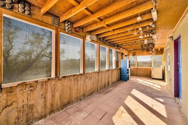 unfurnished sunroom with beam ceiling