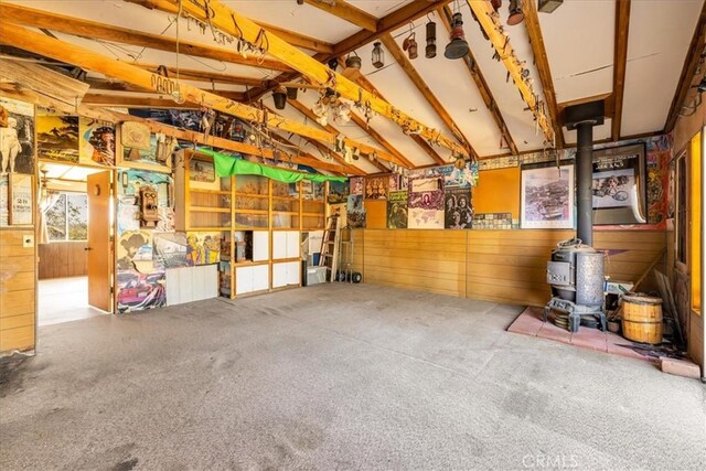 miscellaneous room with vaulted ceiling, carpet flooring, and a wood stove