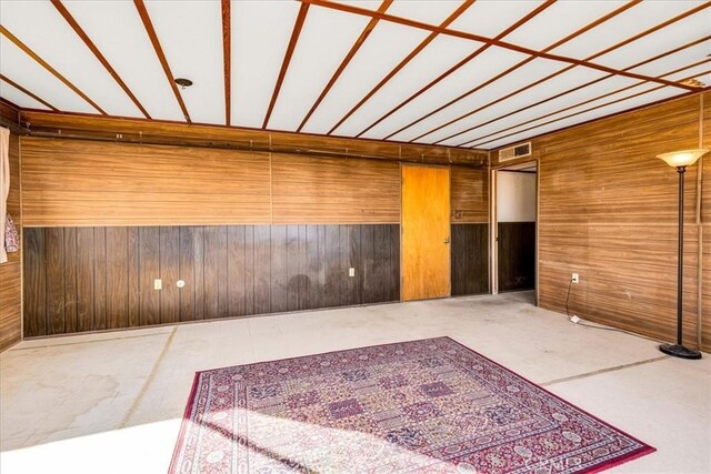 spare room with wooden walls and visible vents