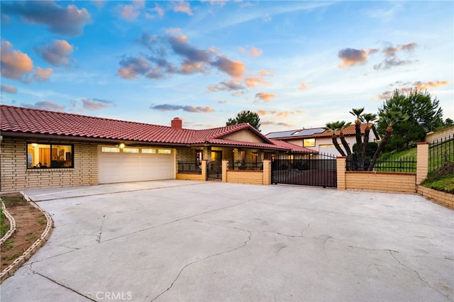 view of front of property featuring a chimney, a tiled roof, fence private yard, a garage, and driveway