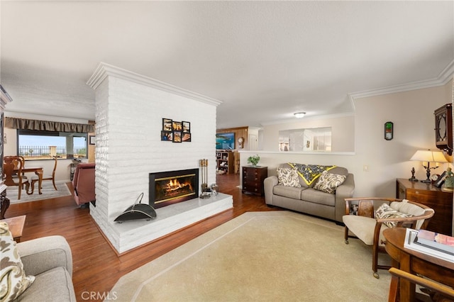 living area featuring wood finished floors, crown molding, and a brick fireplace