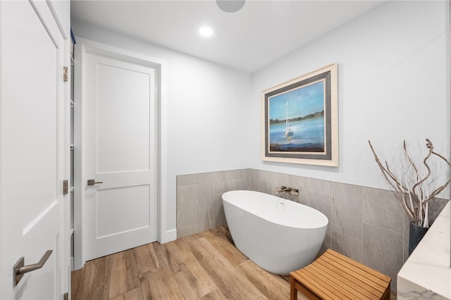 38101 Stone Meadow Dr, Murrieta, CA 92562 - bathroom featuring a freestanding tub, wood finished floors, a wainscoted wall, and tile walls