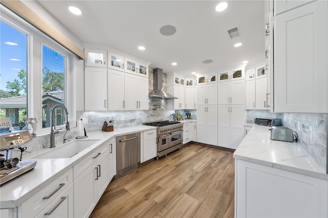 38101 Stone Meadow Dr, Murrieta, CA 92562 - kitchen featuring a sink, white cabinets, wall chimney exhaust hood, appliances with stainless steel finishes, and visible vents