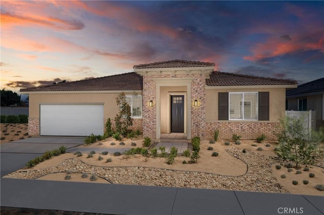 view of front facade with stucco siding, a tile roof, driveway, and an attached garage