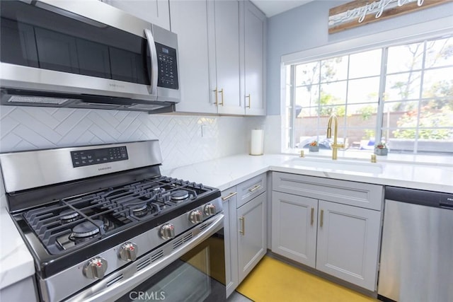 2196 Evergreen Dr, Tustin, CA 92782 - kitchen with appliances with stainless steel finishes, gray cabinets, decorative backsplash, light stone countertops, and a sink