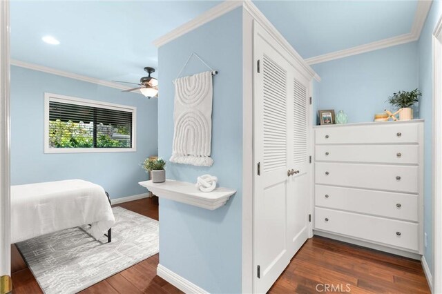 bedroom with dark wood-style floors, a ceiling fan, a closet, crown molding, and baseboards
