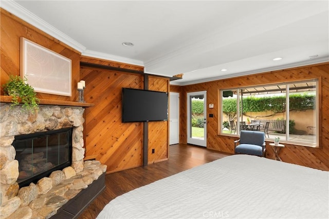 bedroom with crown molding, a stone fireplace, wood finished floors, wood walls, and access to exterior