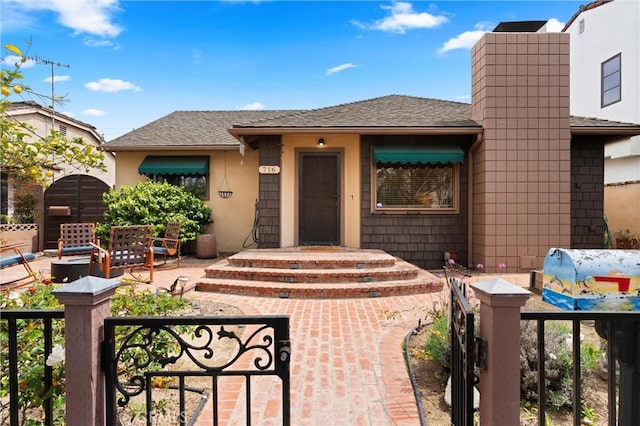 view of front of property with a gate, stucco siding, roof with shingles, and fence