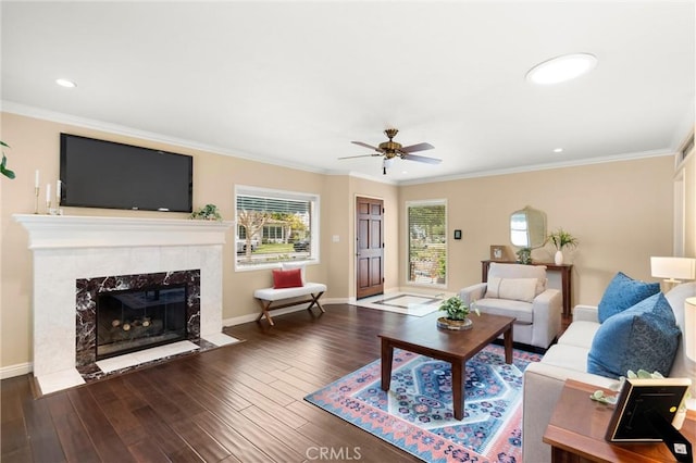 living area featuring wood finished floors, a ceiling fan, baseboards, and ornamental molding