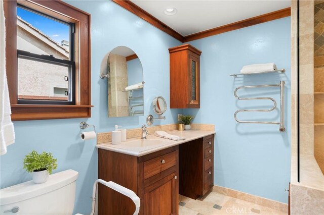 bathroom featuring toilet, ornamental molding, vanity, and baseboards