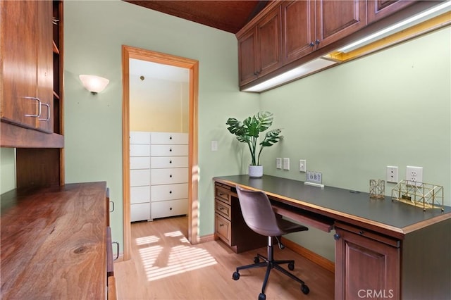 home office with baseboards, light wood-style flooring, and built in desk