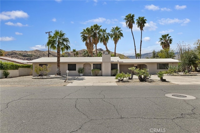 view of front of home with driveway, a mountain view, and stucco siding