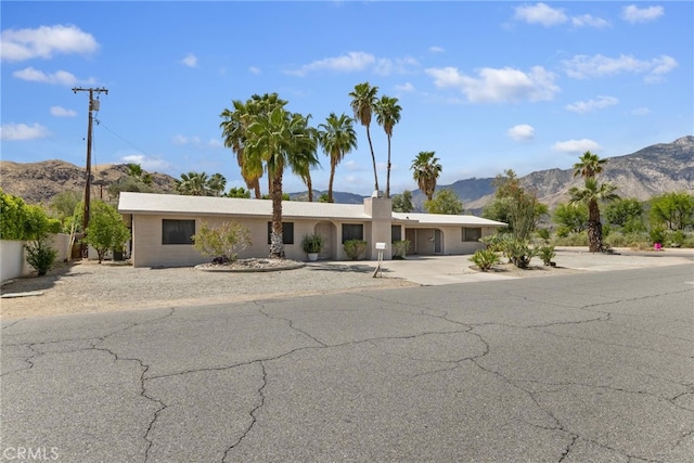 ranch-style house with a mountain view, driveway, and fence