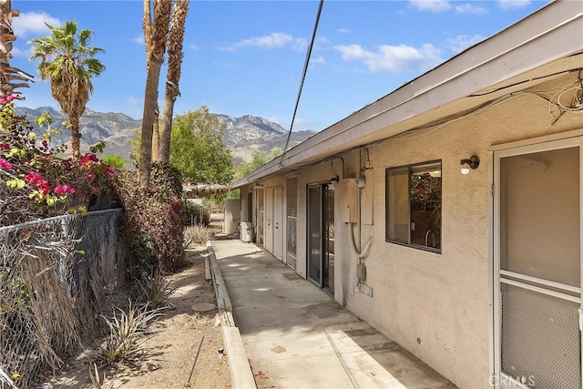 view of home's exterior with a patio, fence, a mountain view, and stucco siding