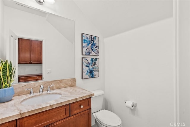 bathroom with toilet, lofted ceiling, and vanity