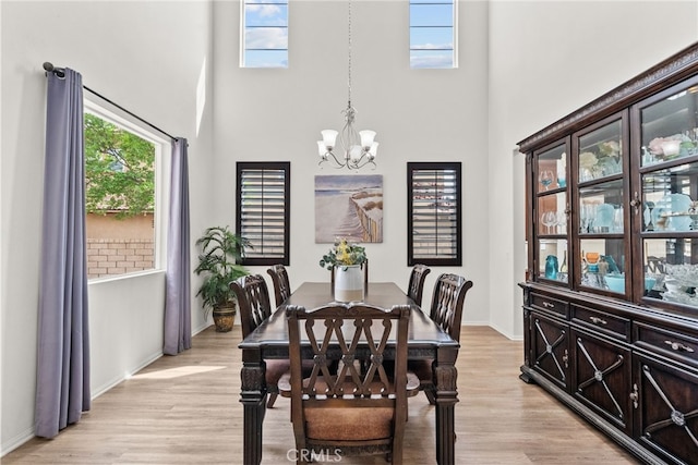 dining space featuring a chandelier, baseboards, and a high ceiling